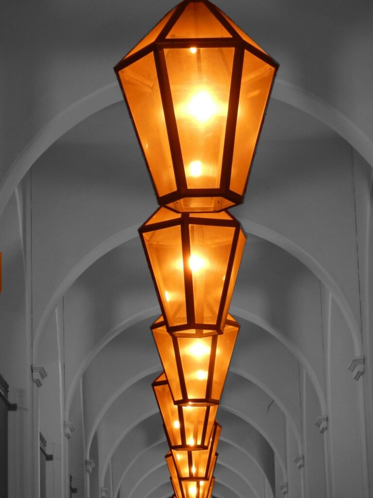 A series of glowing geometric lanterns in a stylish arched hallway, showcasing architectural beauty.