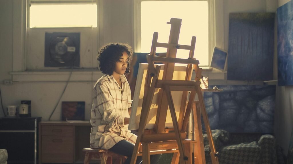 A woman painting on an easel in a warmly lit art studio, expressing creativity.